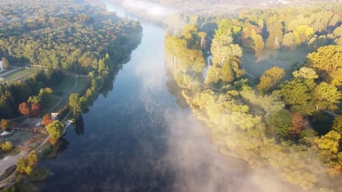 Flying Over River with Calm Reflective Water Surface and White Fog Mist Forest
