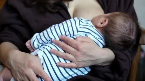 Adult breastfeeding infant in a home environment