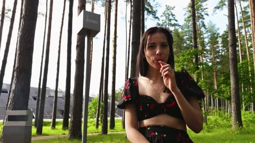 A Woman Blissfully Eats a Popsicle in a Peaceful Forest Park Surrounded By Greenery Sunshine and