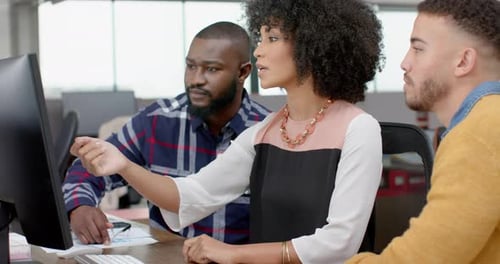 Drei verschiedene männliche und weibliche Kollegen diskutieren im Büro am Computer