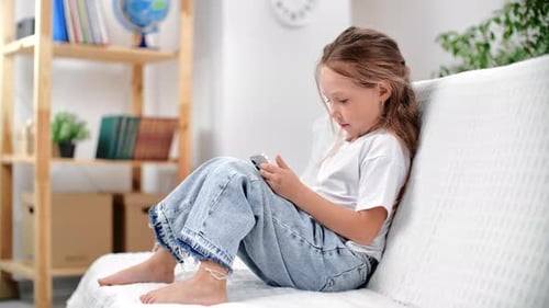 Child Relaxing on Couch Using Smartphone