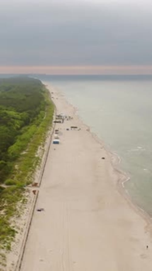 Vertical drone shot rotating over a beach, gloomy, summer evening in Hel, Poland