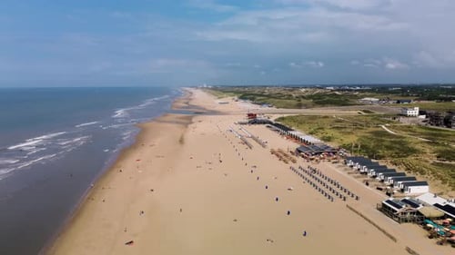 A beautiful aerial view of a sandy beach with rows of beach huts, people relaxing by the shore