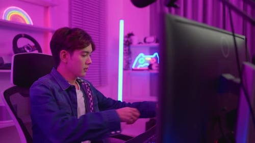 Young Adult Putting On Headphones at Computer