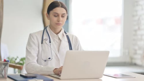Young Female Doctor Working on Laptop in Clinic