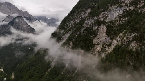 Drone aerial view of clouds drifting over the majestic peaks of the Alps mountains