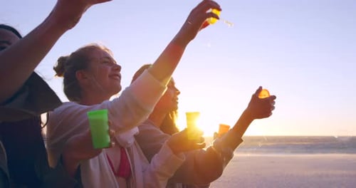 4k video footage of a group of friends blowing bubbles on the beach at sunset