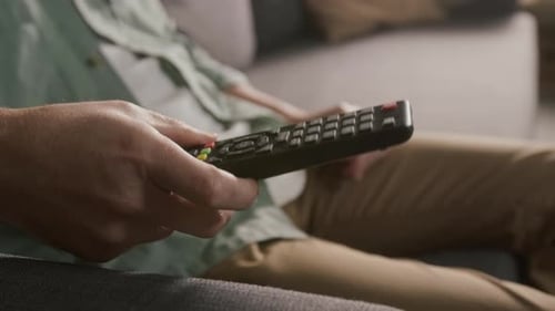Anonymer Zuschauer, der einen Film mit Fernbedienung auf dem Smart TV auswählt