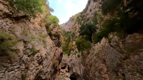 FPV-Drohne rückwärts entlang des Yellow Canyon geschossen, mit Menschen, die am blauen Wasser