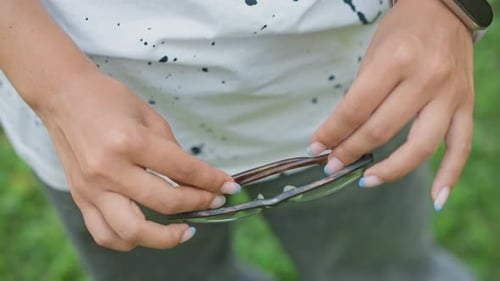 Woman Holding Eyeglasses Outside on a Sunny Day