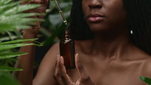 Close Up of Black Woman Holding Bottle of Skincare Serum