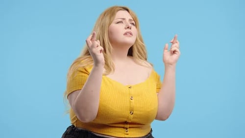 Woman Crossing Fingers on Blue Background