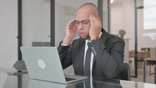 Stressed Professional Working on Laptop in Office