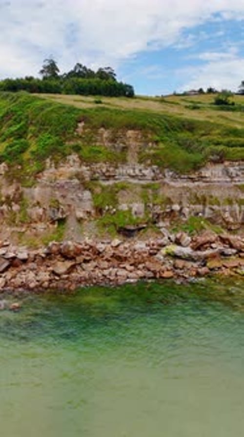 Tranquil view of the waves rolling to the rocky shore. Drone footage distancing from a coast.