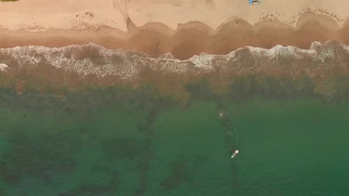 AERIAL: boat in the beach and waves from above.