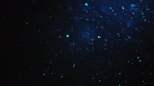 Blaue Glitzerpartikel fallen in Lichtstrahlen