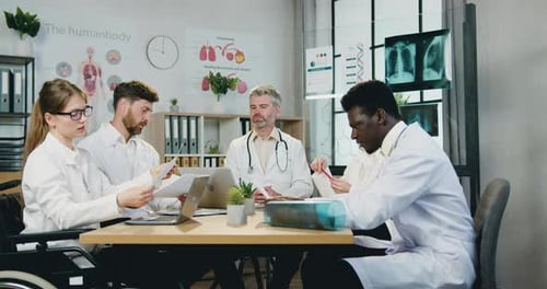 Team of doctors get acquainted with reports during joint meeting in clinic office. Medicine concept.