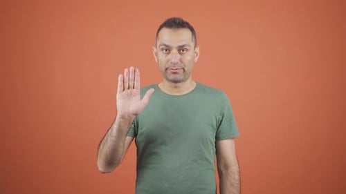 Man Holds Hand Up in a Stopping Gesture