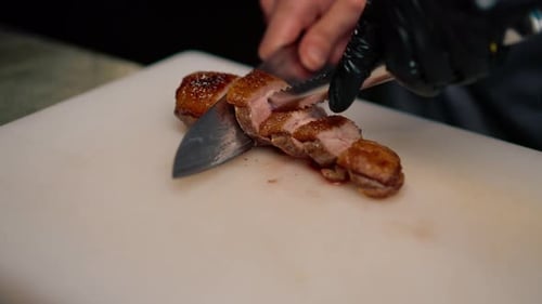 Professional restaurant kitchen chef cuts delicious roasted duck breast with a knife asian cuisine