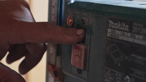Professional Woodworker Pushing Button on a Thickness Planer Machine in Carpentry Workshop