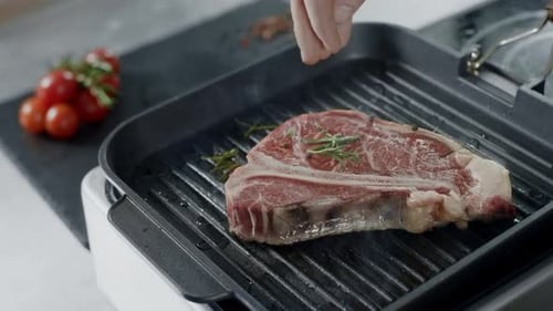 Chef Peppering Frying Meat At Griddle. Closeup Man Hands Cooking Steak In Slow Motion. Close Up H...