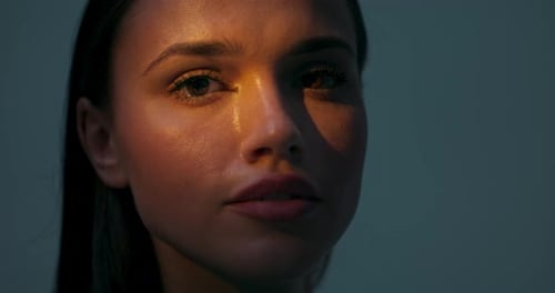 Portrait en gros plan d'une femme sérieuse et concentrée dans un studio blanc et sombre avec une lumière vive