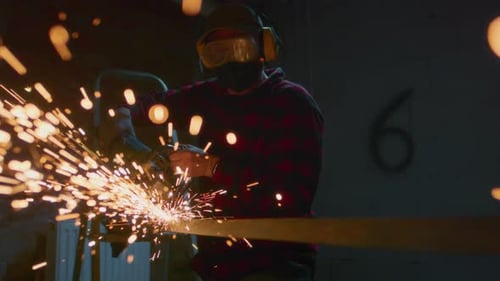 Man Working at Factory Cuts Metal with a Grinder Male at a Construction Site Cuts Off Piece Guy