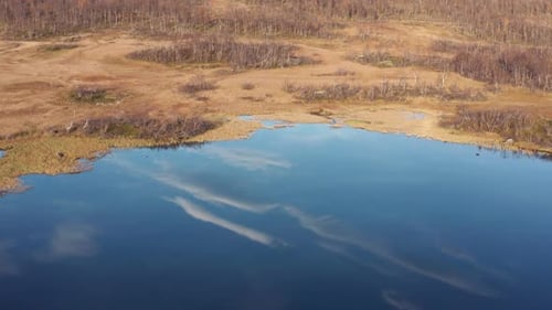 Aerial view of the Norwegian marshland. Clouds reflected in the mirrorlike surface. Slow-motion, pan