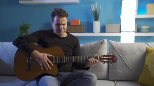 Man Plays Acoustic Guitar in Home Interior