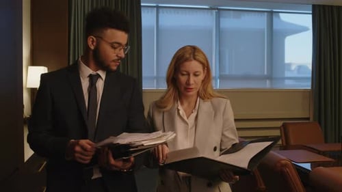 Lawyer Showing Documents to Her Colleague Walking around Meeting Room