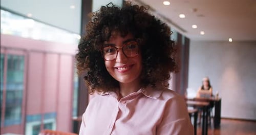 Smiling Woman with Curly Hair in Urban Workplace