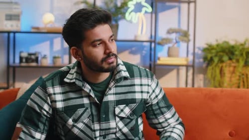 Man Resting on Couch Puts Hand to Face