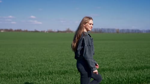Attractive young woman walking on green field.
