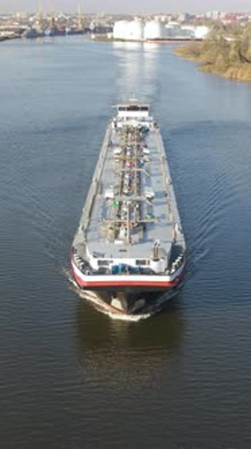 Exploring the journey of an oil tanker navigating through a bustling port on a clear autumn day.