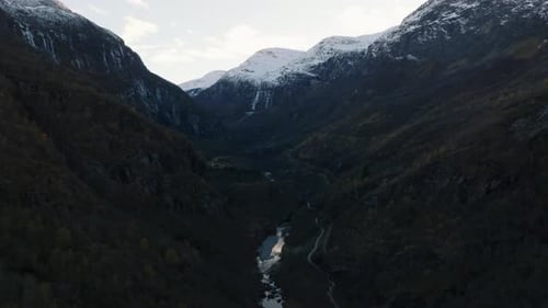 Luftaufnahme einer Flammenbahn mit fahrendem Zug in einer Schlucht in Bergen, die aus einem Tunnel in Norwegen herausfahren
