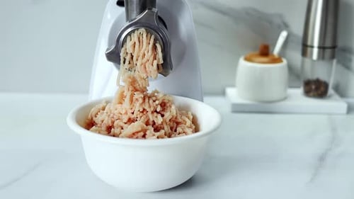 The process of grinding meat in an electric meat grinder close-up.