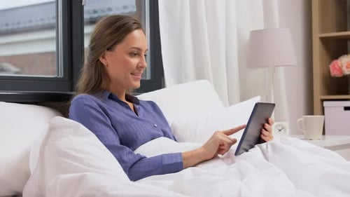 Woman in Bed Using Tablet Device in Bedroom