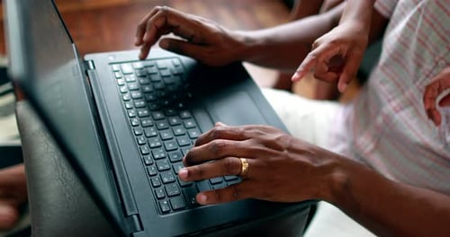 Concentrated Man Typing on Laptop While Child Hugs Him at Home