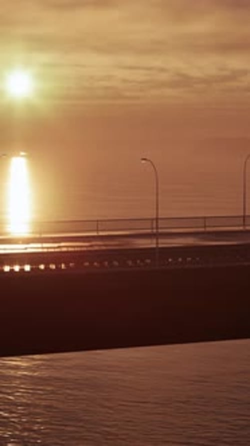 Sun Setting Over Ocean With Bridge in Foreground