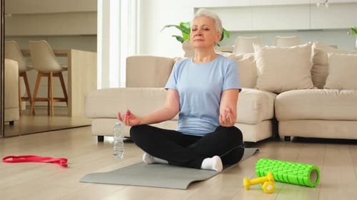 Senior Woman Meditating at Home on Exercise Mat
