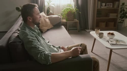 Man Relaxing on Sofa Watching TV in Living Room