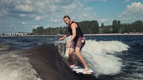 A Young but Experienced Wakesurfer Glides Along the Wave A Man Rides a Boat on the River Summer