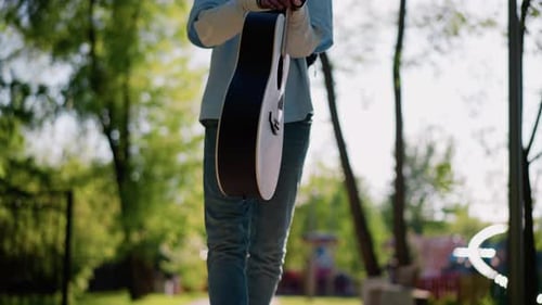 Guitarist Journeys Through Sunny Park Avenue Toward Performance Musician in Casual Attire Proceeds
