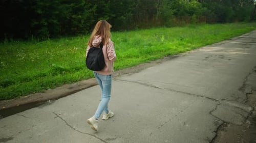 Girl Walking Thoughtfully Along Forest Path with Backpack