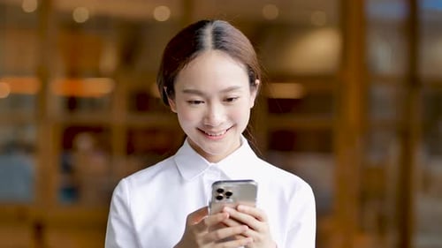 Woman Smiling While Using Smartphone Indoors