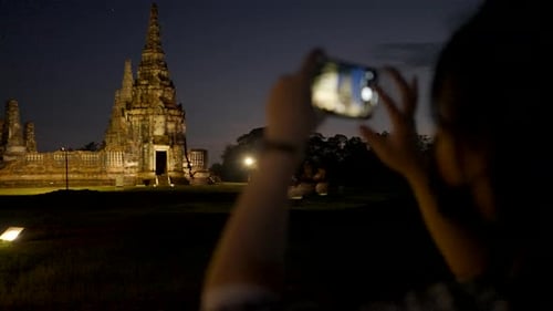 Traveler Girl in Mask Takes a Picture of Wat Yai Chai Mongkhon Temple in Ayutthaya at Night Thailand