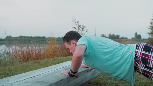 A Young Guy Does PushUps In The Early Morning In Nature Behind Lake Or A Quarry