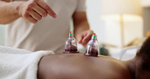 Person, back and cupping therapy as spa treatment for healing or blood flow benefits