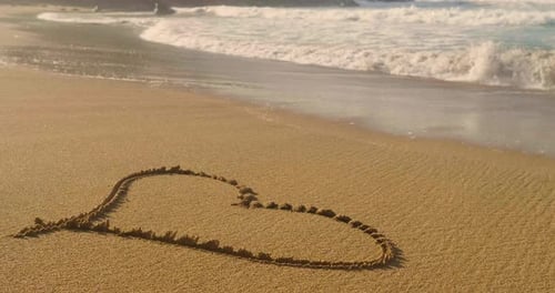 Schönes gemaltes Herz auf braunem Sand, Sonnenuntergang, Meereshintergrund. Konzept: Ruhe, Liebe, Stil, Leben, Sex