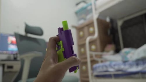 Hand Holding Brightly Colored Toy Gun Close Up